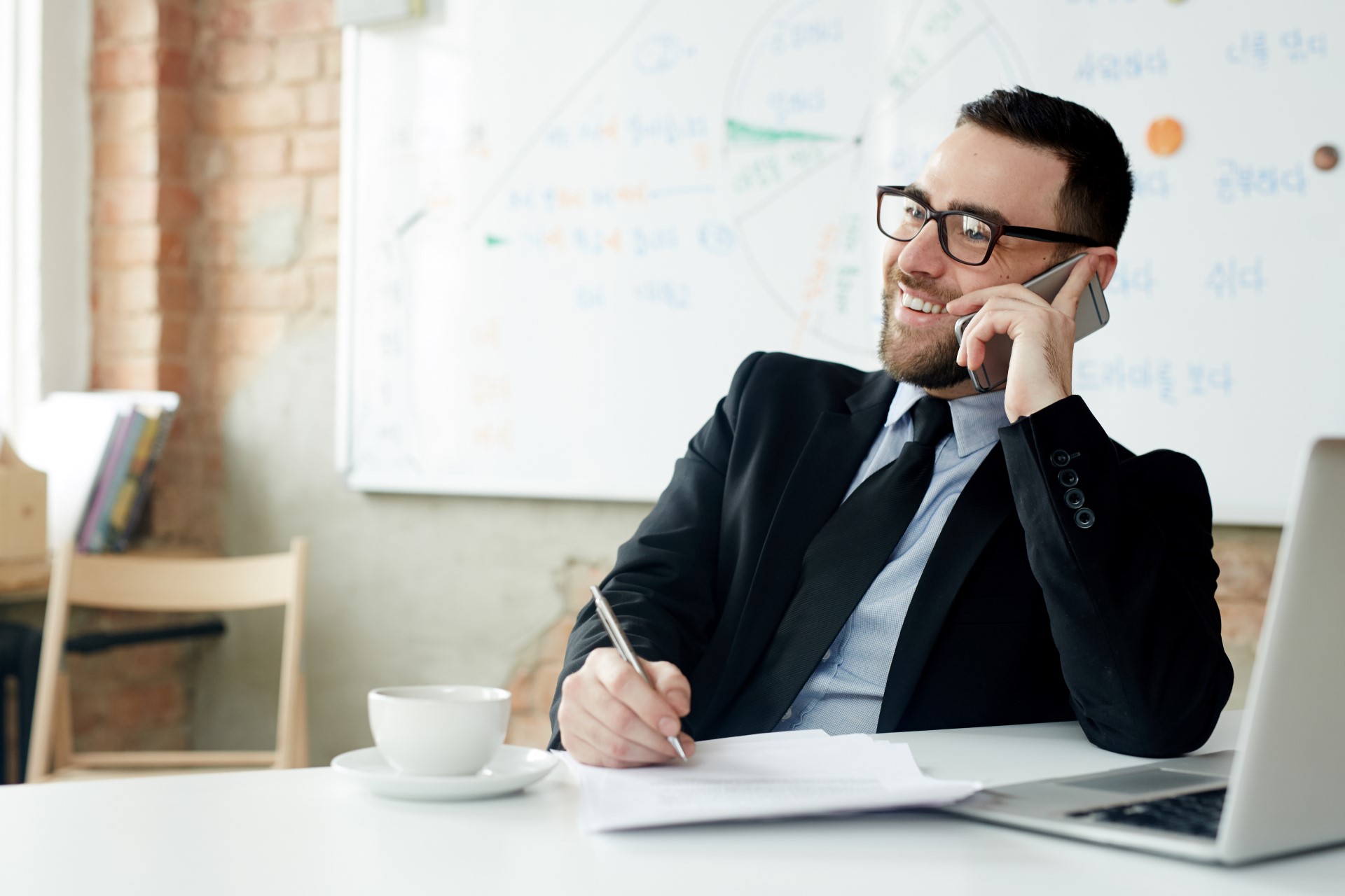 Insurance-agent-calling-on-mobile-sitting-at-office-desk-Car Insurance in Michigan-Insurance Agent in Michigan