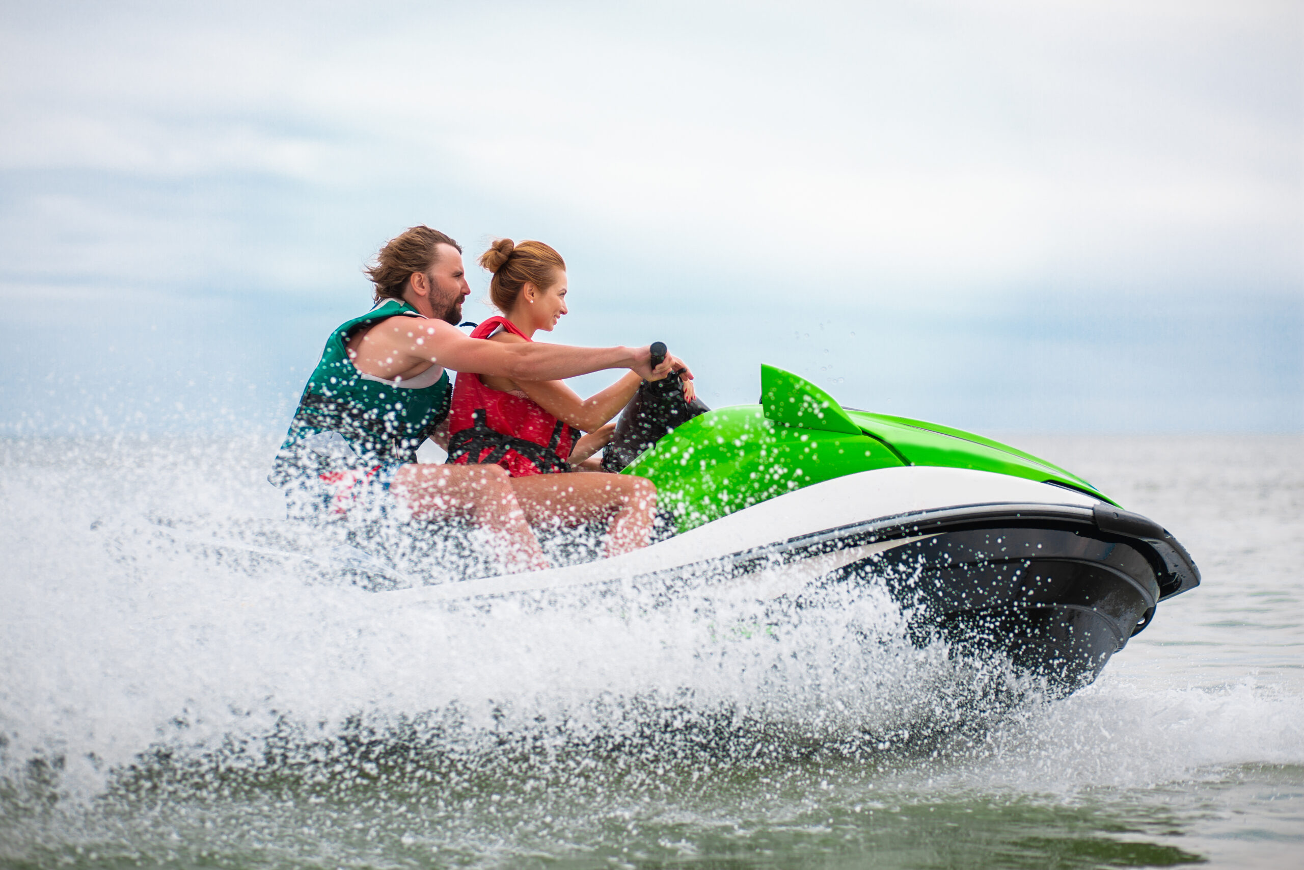 young people having fun driving on high speed on water scooter, man and woman on summer vacation, friends doing active sport-Car Insurance in Michigan-Toy Insurance in Michigan